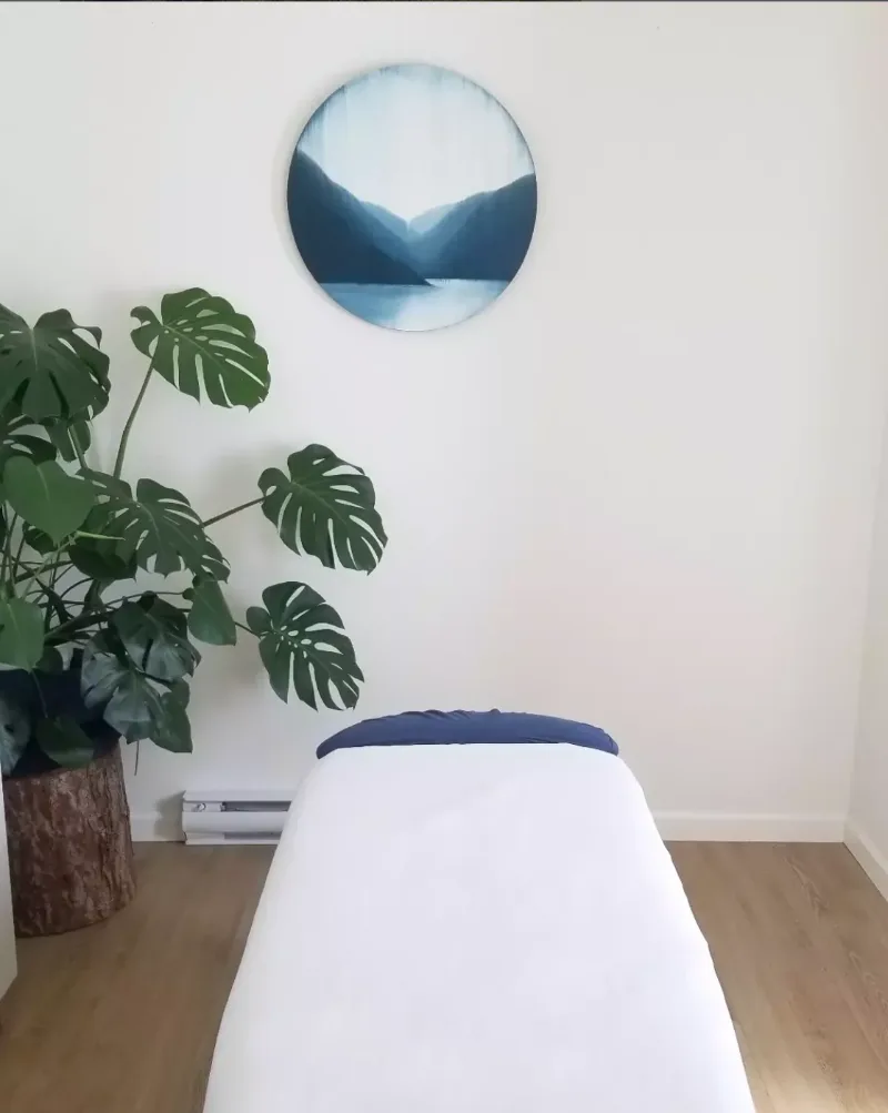 Massage therapy treatment room at Multidimensional Health, Nanaimo BC — linen table, plant, and coastal-toned artwork.
