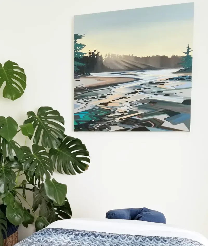 Treatment room at Multidimensional Health featuring a Vancouver Island coastal-estuary painting above the massage table, with a monstera plant alongside.